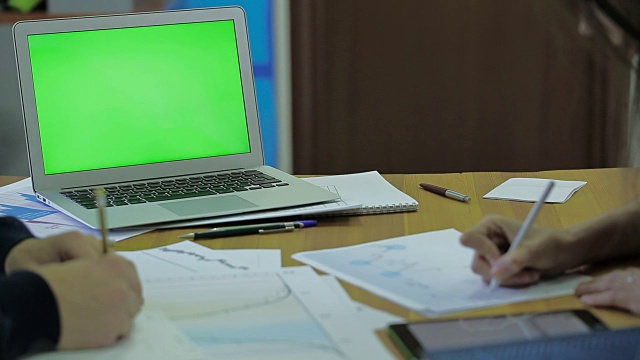木质办公桌和带有模拟屏幕的轻薄笔记本电脑，有文本空间，有财务时间表条目和标记的工作男女视频下载