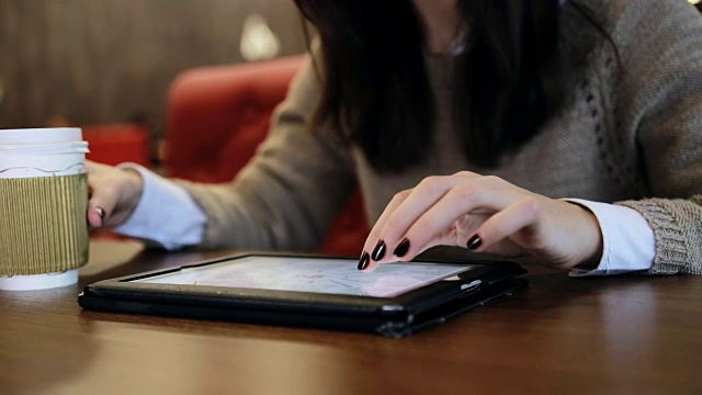 一个女人在咖啡馆里用着平板电脑视频下载