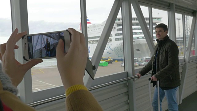 一个带手机的女人在船坞给一个男人拍照视频素材