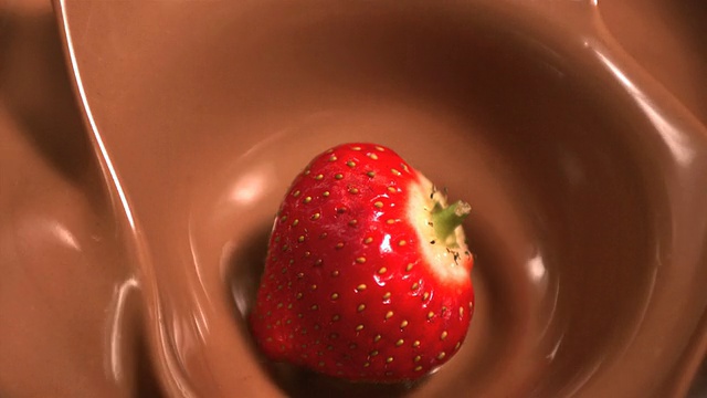 近距离观察草莓落入融化的巧克力视频素材