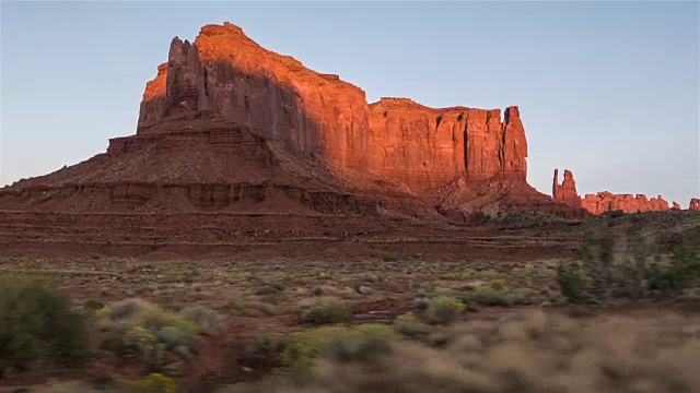 驾驶美国:日落时从汽车侧窗拍摄的纪念碑谷的沙漠台地和山丘视频下载