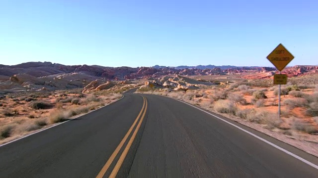 驾驶美国:汽车驾驶的观点通过美丽的沙漠景观在一个空的道路通过火谷，内华达州视频下载