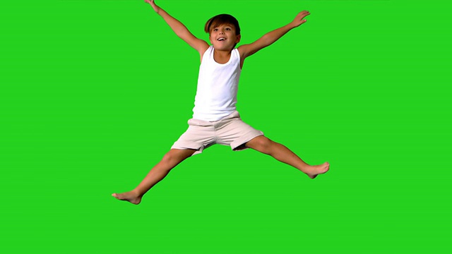 快乐的小男孩在绿色的屏幕上跳跃视频素材