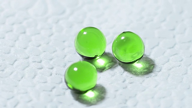 三个绿色透明药片在白色背景上旋转视频下载