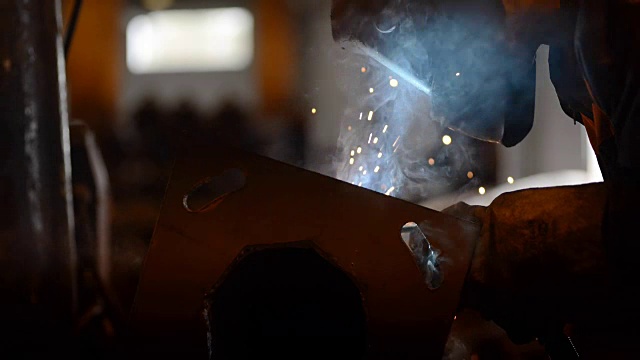 焊接工程师完成焊接金属。许多明亮的火花，烟雾和光。建设和制造右近景侧面肖像视频素材