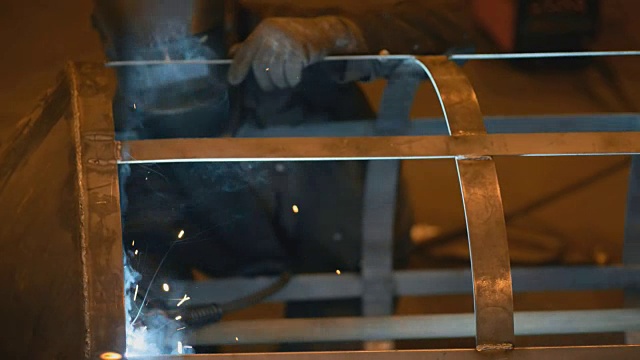 焊接工程师完成金属罐的焊接单元骨架。许多明亮的火花，烟雾和光。建设和制造右侧视图肖像视频素材