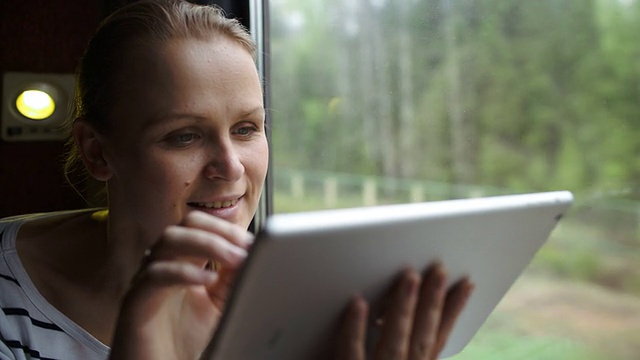 年轻女子用触摸板坐在窗边视频素材