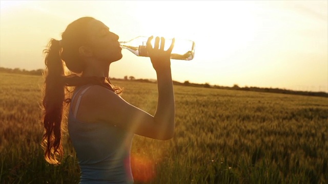 炎热的夏天日落女人喝水疲惫的跑步者视频下载