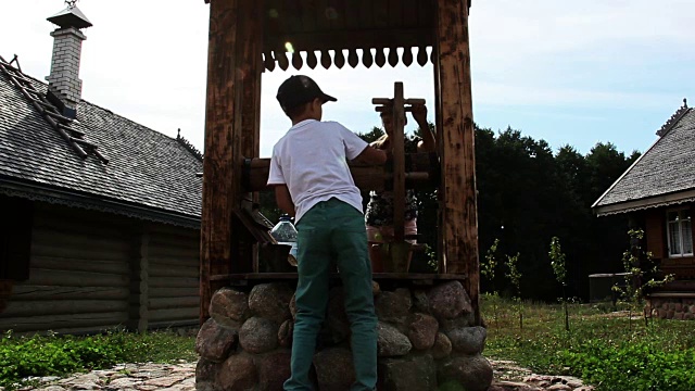 在俄罗斯的一个村庄里，一个男孩和一个女孩从井里打一桶水视频下载