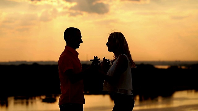 夕阳下的爱情剪影。跳舞和亲吻。视频素材