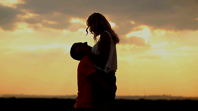 夕阳下的爱情剪影。亲吻和拥抱。视频素材