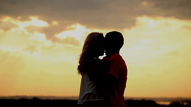 夕阳下的爱情剪影。充满激情的吻。视频素材