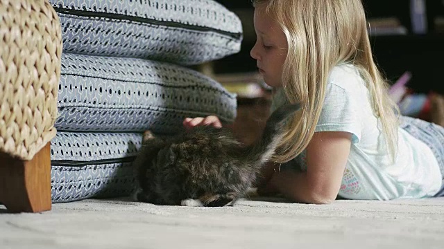 一个小女孩躺在地板上抚摸着一只想要逃跑的小猫视频下载