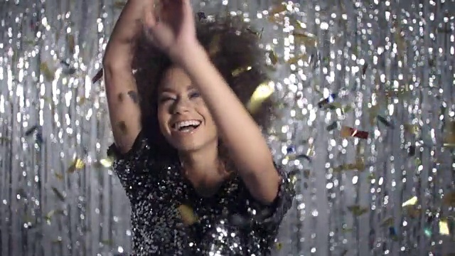 美丽的美国黑人女子在金色的五彩纸屑间跳舞，慢镜头。视频素材