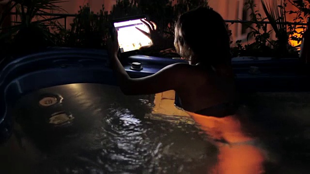 豪华水疗-女人冲浪在平板电脑上在漩涡浴-按摩浴缸视频下载
