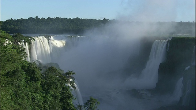 从巴西和阿根廷边境的伊瓜苏瀑布上倾泻而下的水流中缩小镜头视频素材