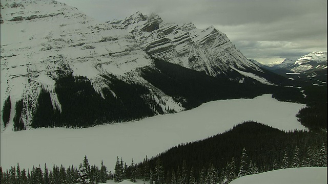 加拿大落基山公园，季节性的雪融化在山上，露出森林山坡和蓝色的湖视频素材