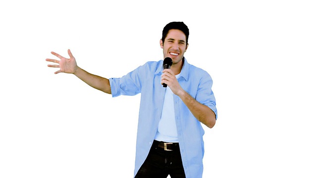 一名男子对着白色背景的麦克风唱歌视频素材