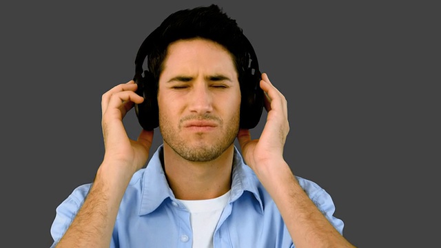 灰色背景下戴着耳机听音乐的男人视频素材