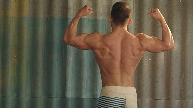 健美运动员强壮的运动肌肉男，展示他的男性肌肉，向后站着视频素材