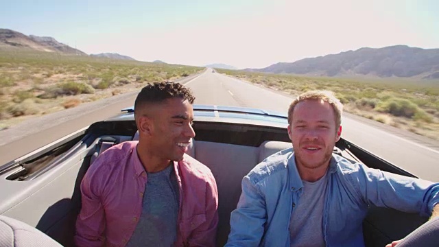 两个男性朋友在公路旅行在敞篷车拍摄的R3D视频素材