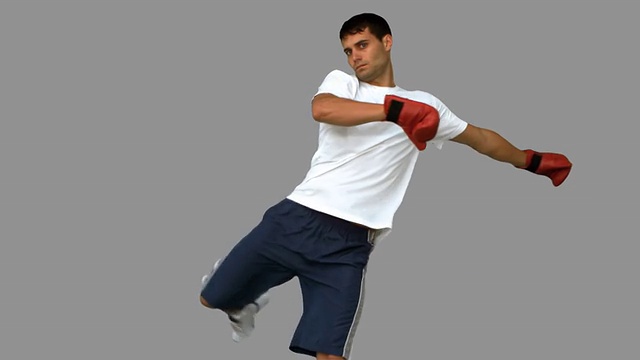 英俊的拳击手在灰色屏幕上表演空中踢视频素材