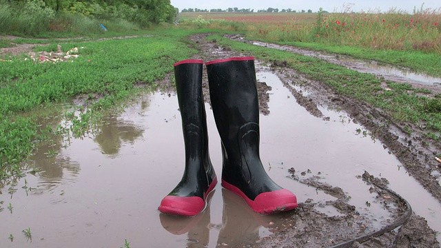 雨后胶靴在泥泞的乡间小路上踩水坑视频素材