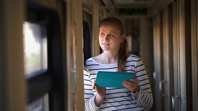 火车上一个年轻女子拿着垫子站在窗边视频素材