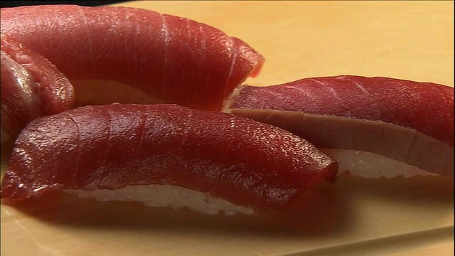 四个椭圆形的金枪鱼手握寿司放在切菜板上。视频下载