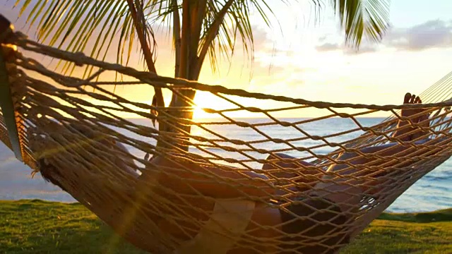 日落时分，浪漫的情侣在热带吊床上放松。夏天豪华度假。视频素材