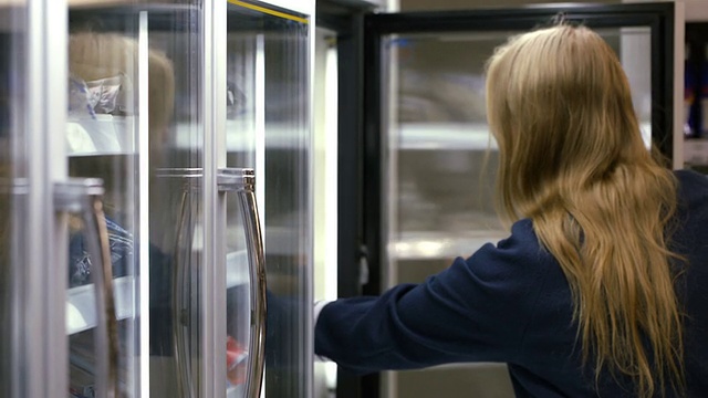 在商店里从冰箱里拿冷冻食品的女人视频素材