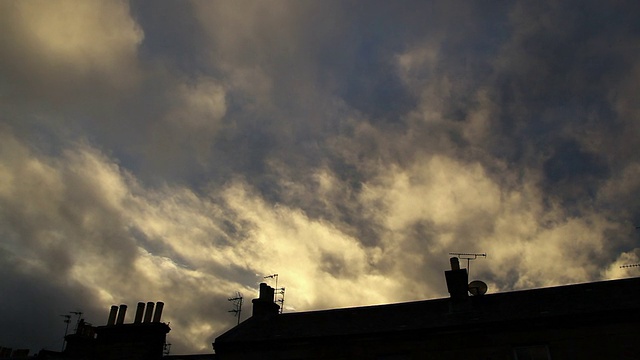 日落时的云朵飘过屋顶和烟囱视频下载