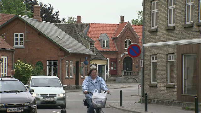 骑自行车的人和司机在丹麦萨姆索镇中心大街上穿梭。视频下载