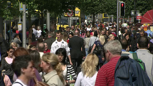 行人挤在都柏林的人行横道上，双层旅游巴士开过。视频下载