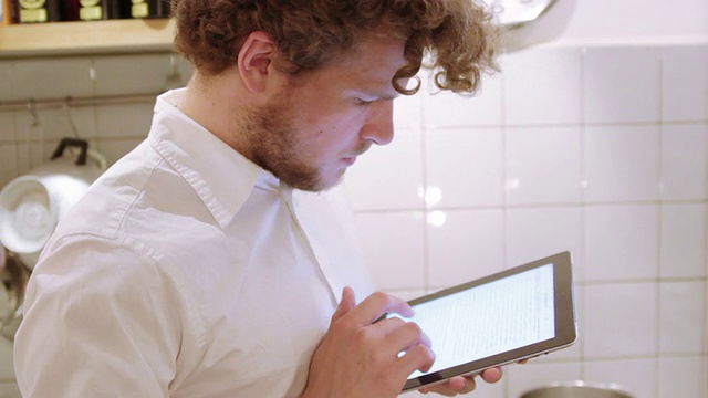 一个男人在厨房里用iPad视频素材