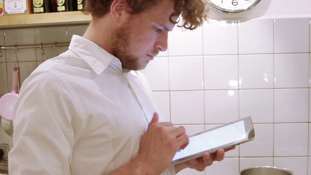 一个男人在厨房里用iPad视频素材