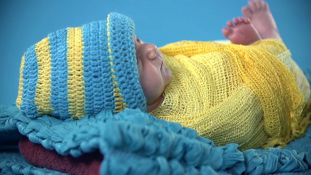 婴儿躺在盖着彩色床单的蓝色毯子上视频下载