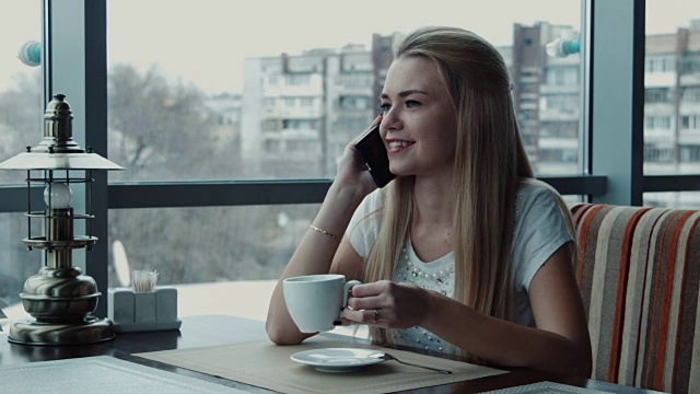 女孩在咖啡厅里一边喝茶一边打电话视频素材