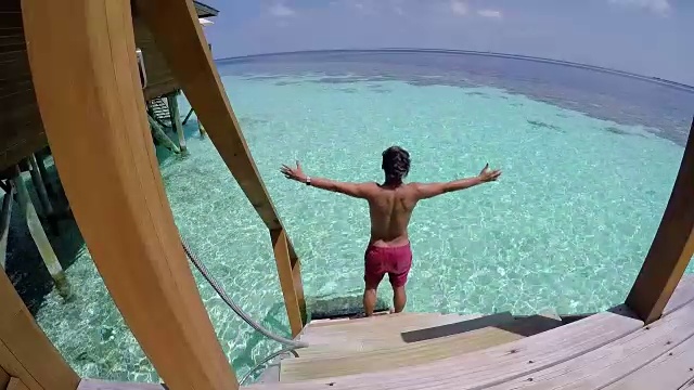 一个年轻人从房间走到海里，马尔代夫的海边度假胜地。视频下载