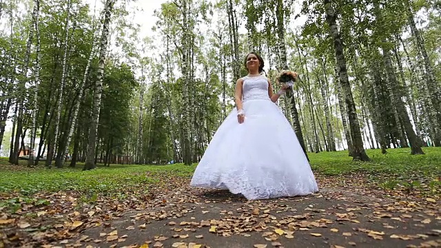 新娘穿着婚纱带着花束在公园里散步视频素材