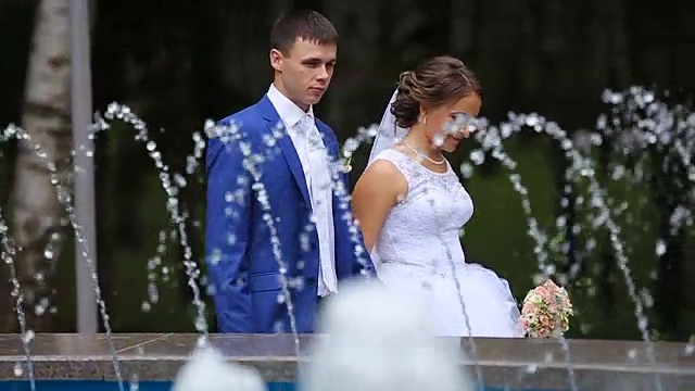 快乐的新娘和新郎在公园喷泉附近散步视频素材