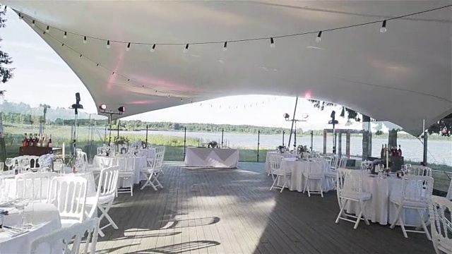 婚礼在一家户外餐厅举行，一切都已准备就绪。湖边夏日露台上的婚宴装饰全白。Flycam视频下载