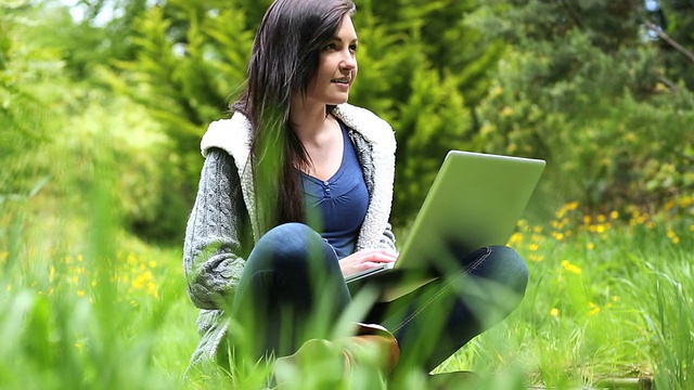 坐在草地上用笔记本电脑的女人视频素材