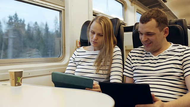 年轻人在火车上一边看平板电脑一边说话视频素材