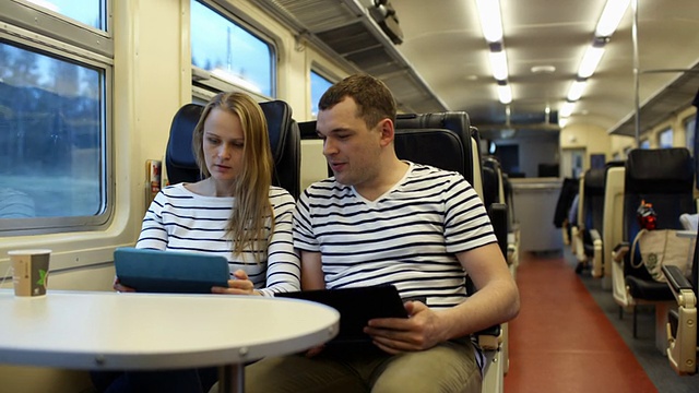 拿着垫子的女人和手提电脑的男人在火车上聊天视频素材