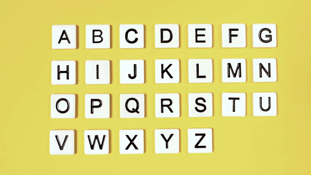 塑料字母弹跳和显示字母在黄色的表面视频下载