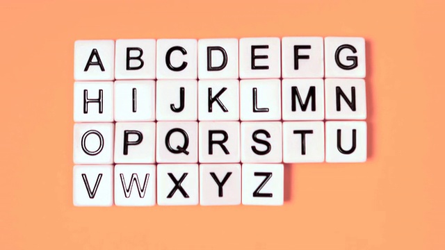塑料字母弹跳和显示字母在橙色的表面视频下载