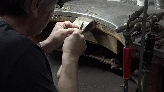 戈德史密斯正在用锉刀和砂纸打磨一枚金戒指视频素材