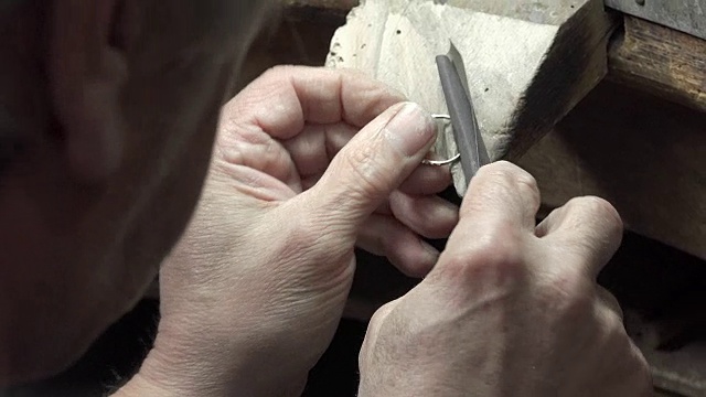 戈德史密斯正在用锉刀和砂纸打磨一枚金戒指视频素材