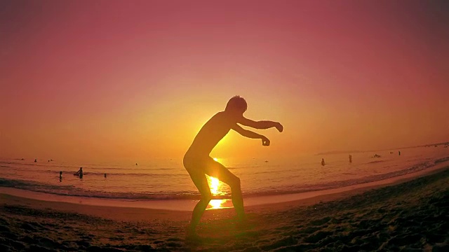 跑酷自由奔跑者在夏日海滩上的日落边跑边后空翻。斯坦尼康慢动作镜头视频素材